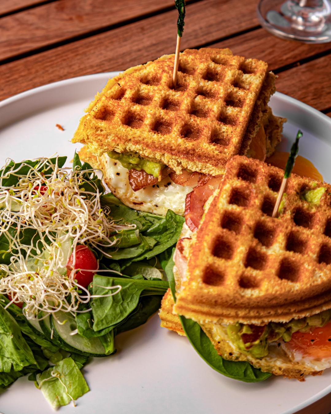 Sándwich de waffle con huevo, tocino y ensalada